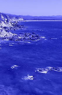 Paisaje costero de acantilados y océano en México con filtro azul corporativo, simbolizando la infraestructura y las rutas de transporte internacional de mercancías por mar y aire.